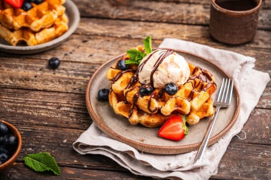 Belgian waffles vs pancakes featuring an Icki Sticki Belgian waffle topped with banana whipped cream and pecans