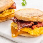 Breakfast sandwich filling with scrambled egg bacon and melted cheddar cheese on a toasted English muffin