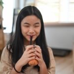 What is boba tea showing a young girl enjoying a boba tea drink with tapioca pearls and wide straw