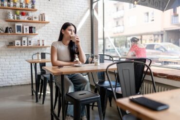 Woman relaxing with a drink at an uncrowded table, outside coffee shop peak hours in Verona, WI