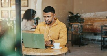 Man working on a laptop with headphones in at a laptop-friendly coffee shop in Verona, WI