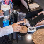 Customer using a phone to pay while picking up a coffee order after choosing to order ahead for pickup