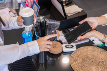 Customer using a phone to pay while picking up a coffee order after choosing to order ahead for pickup